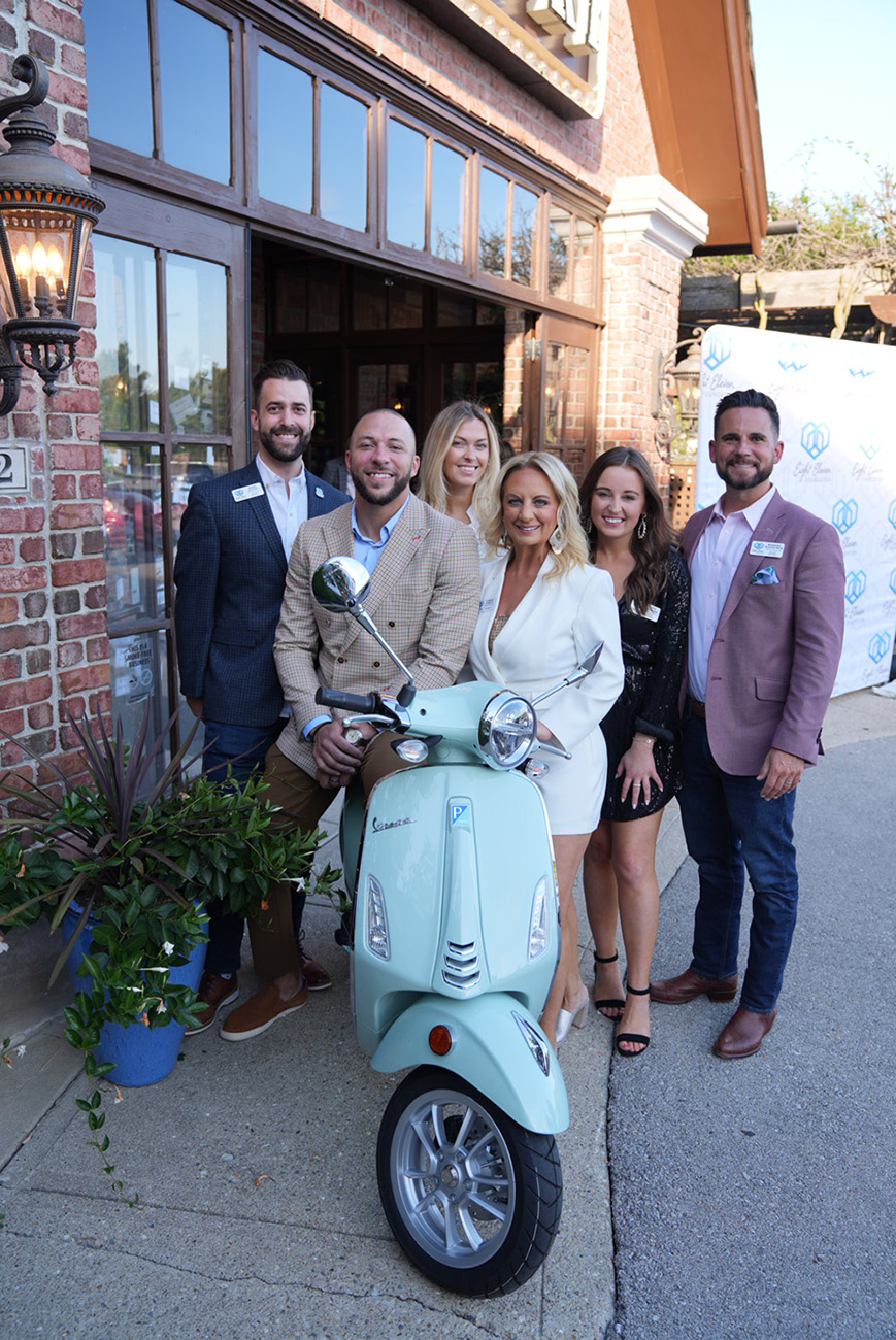 The Eight Eleven Foundation’s Board poses with a 2023 Vespa Primavera 50 that was auctioned off during the evening. <b>Not Pictured: Allison Russo and Jeremy Hunt.